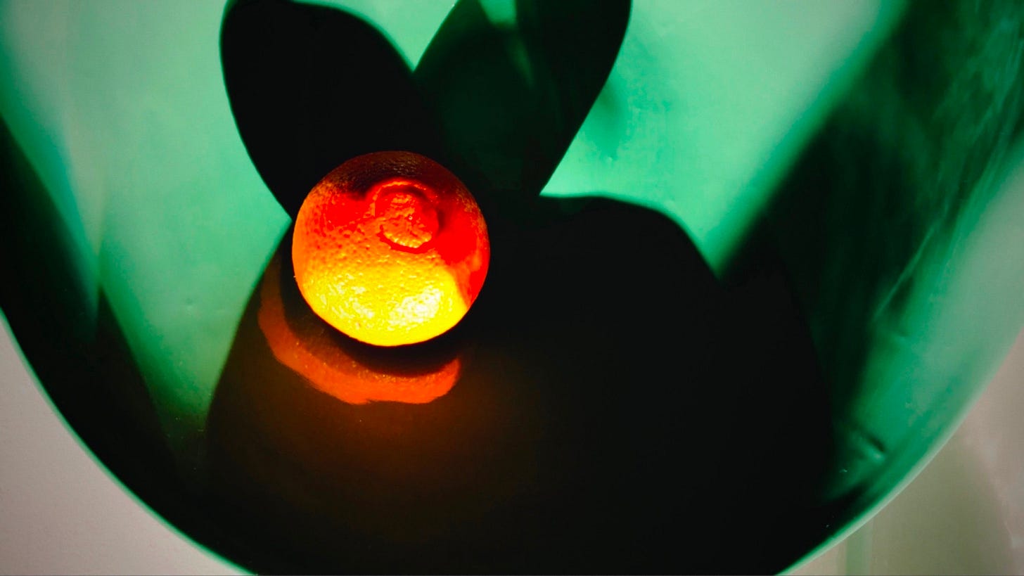 A photo of an orange in a green bowl