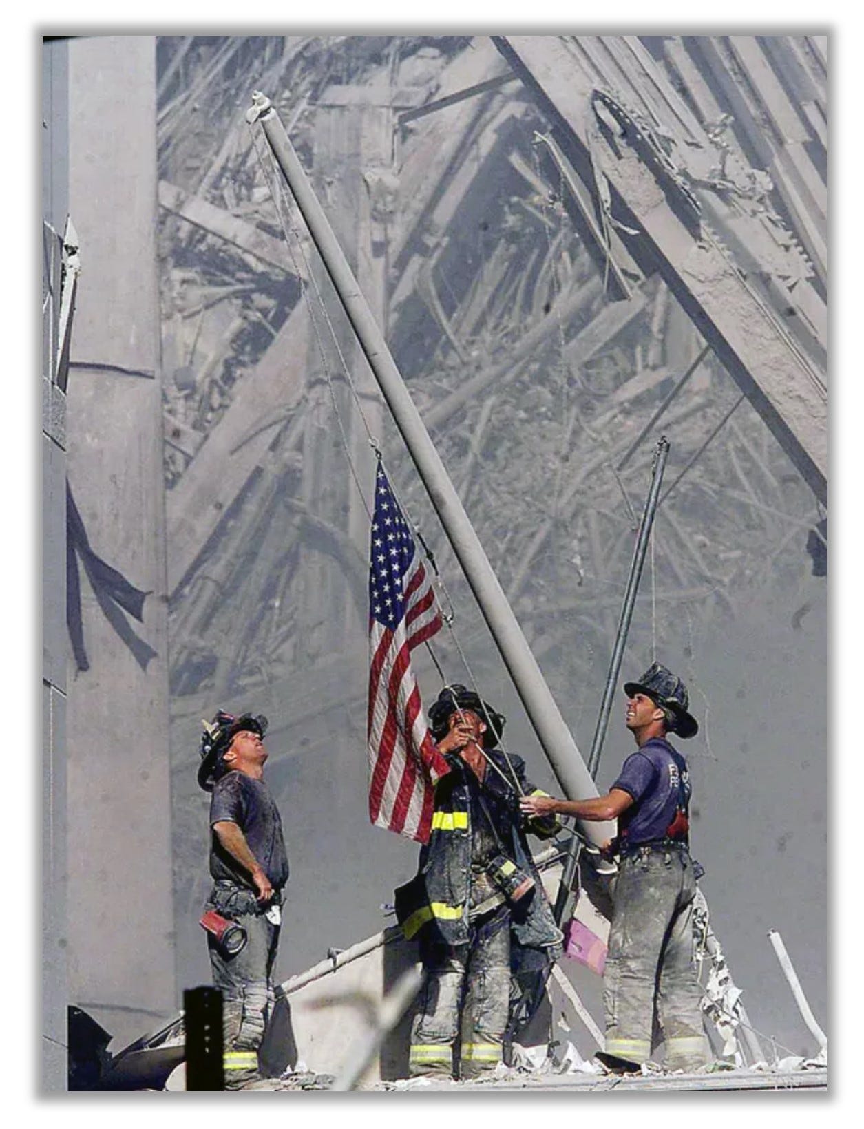 Firefighters raise a flag over the smoldering remains of the World Trade Center.