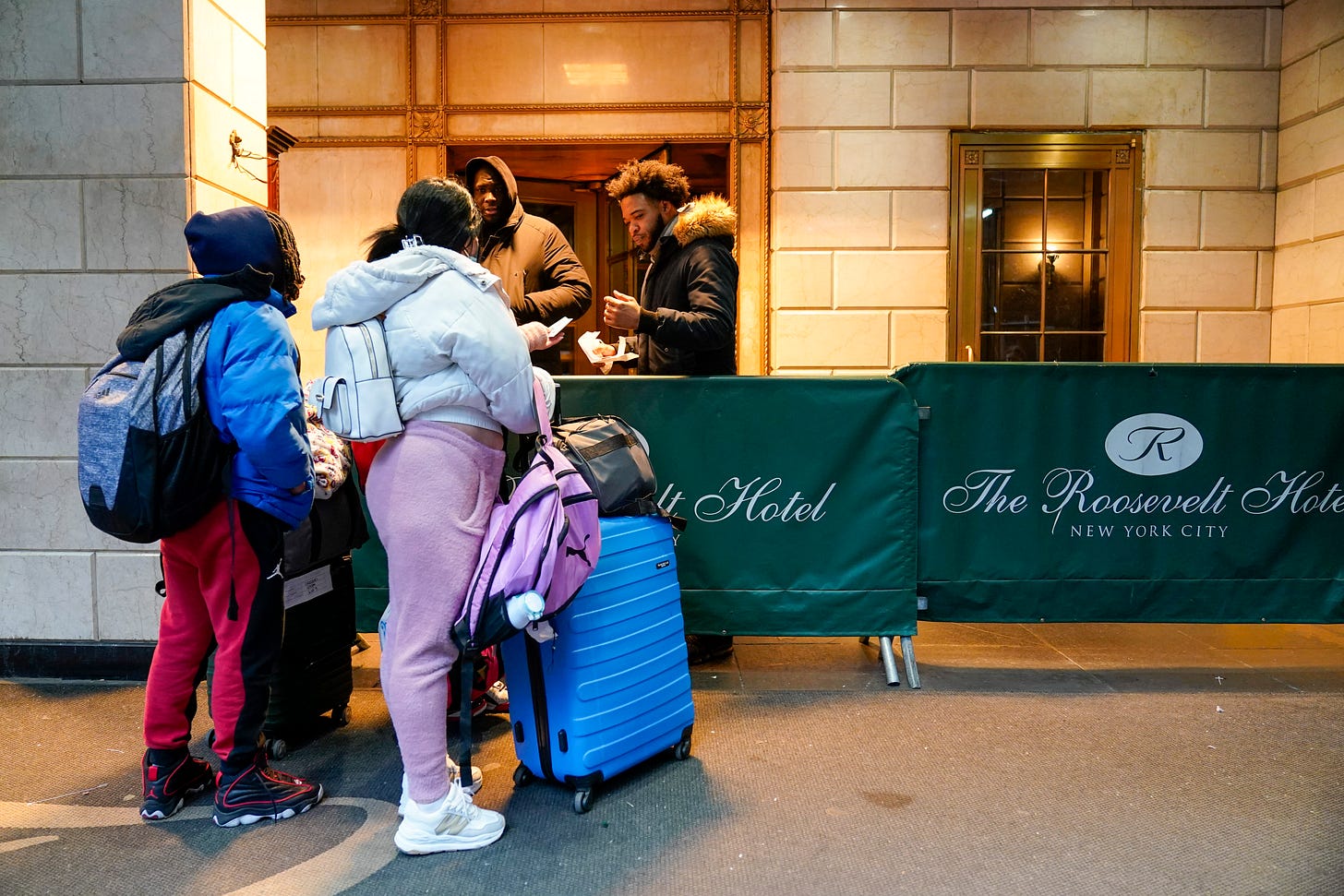 An immigrant family show their paperwork to security guards at the Roosevelt Hotel, Tuesday, Jan. 9, 2024, in New York.
