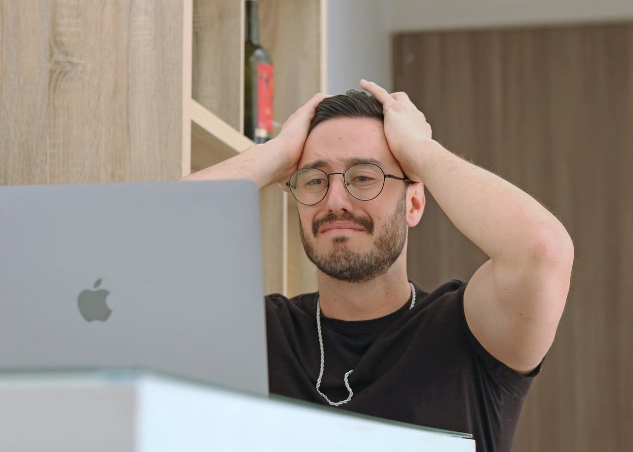 Man upset about mistake. He is wearing a black shirt and standing in front oa macbook. Man upset about mistake. He is wearing a black shirt and standing in front oa macbook.