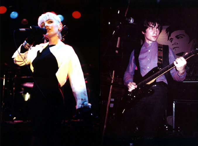 The Primitives on stage. A blonde female singer dressed in black and white, and a male guitarist wearing a purple shirt.