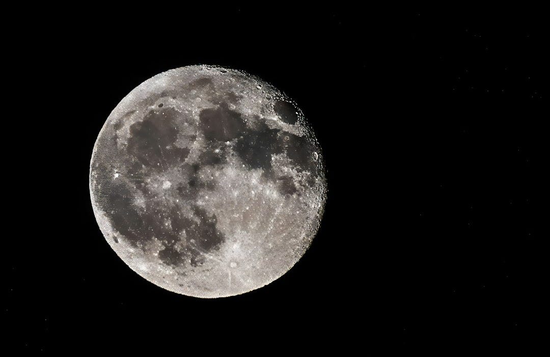 A full moon is seen in the dark sky