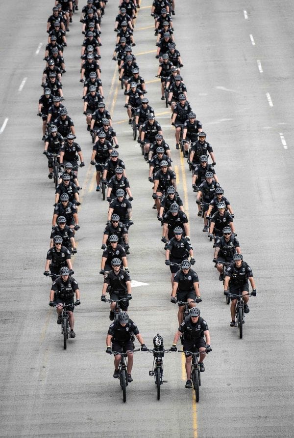 Defile de policier dont deux a l'avant tenant un troisieme velo sans cycliste
