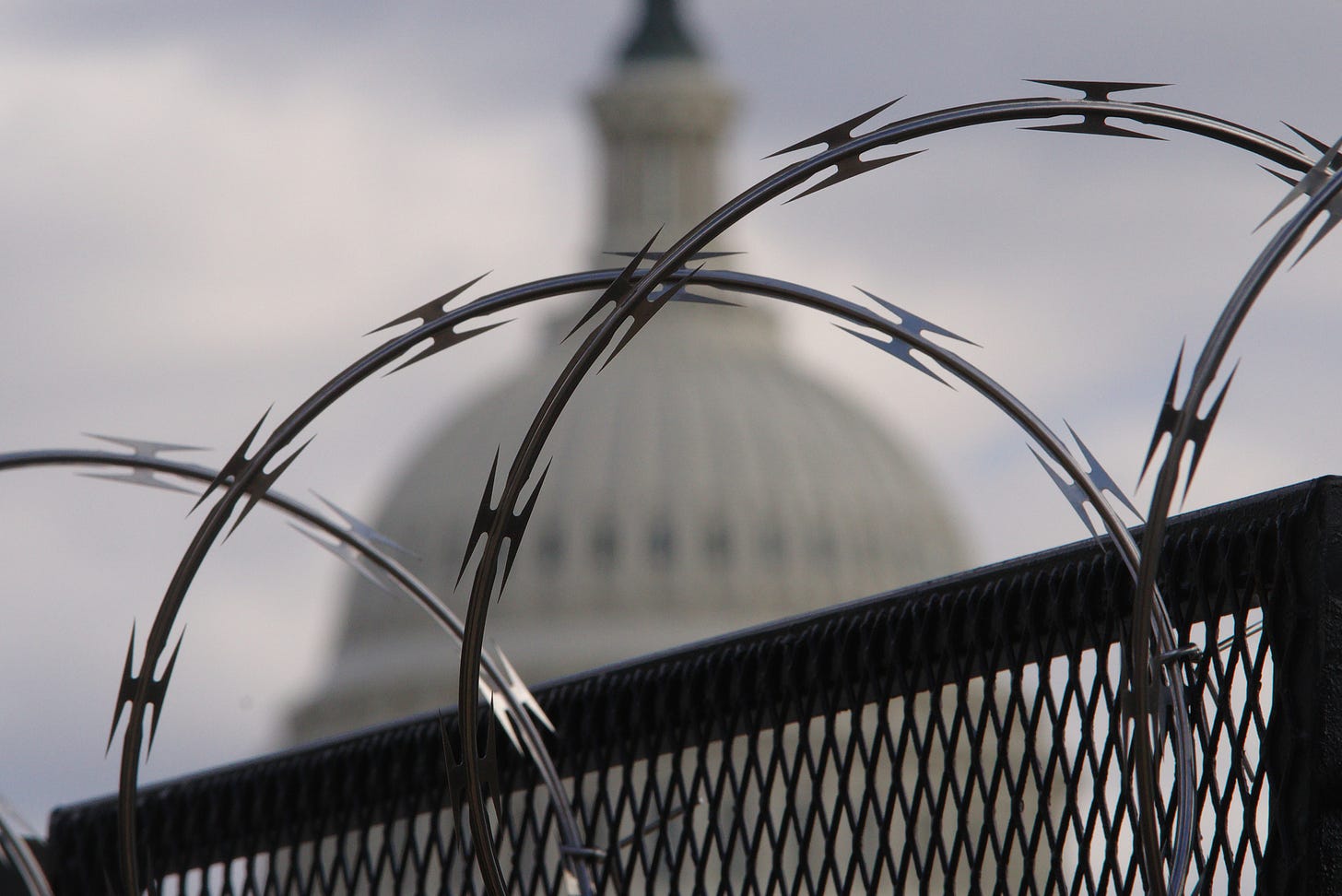 The U.S. Capitol with barbed wire in the foreground.