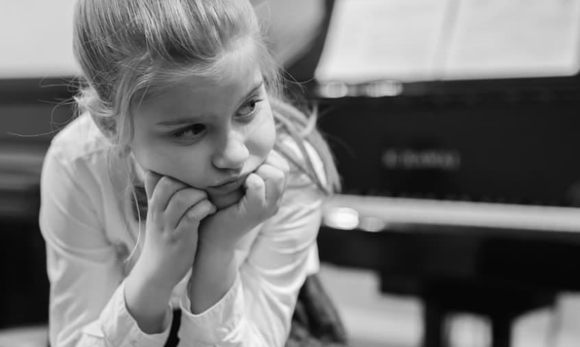 contemplative young girl next to piano