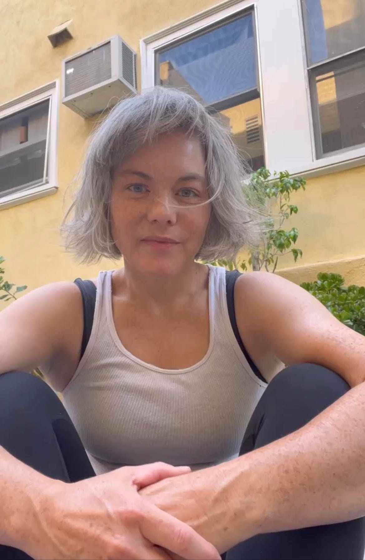 A photo of the author in her running gear: a white Hanes singlet, plain sports bra, and leggings.