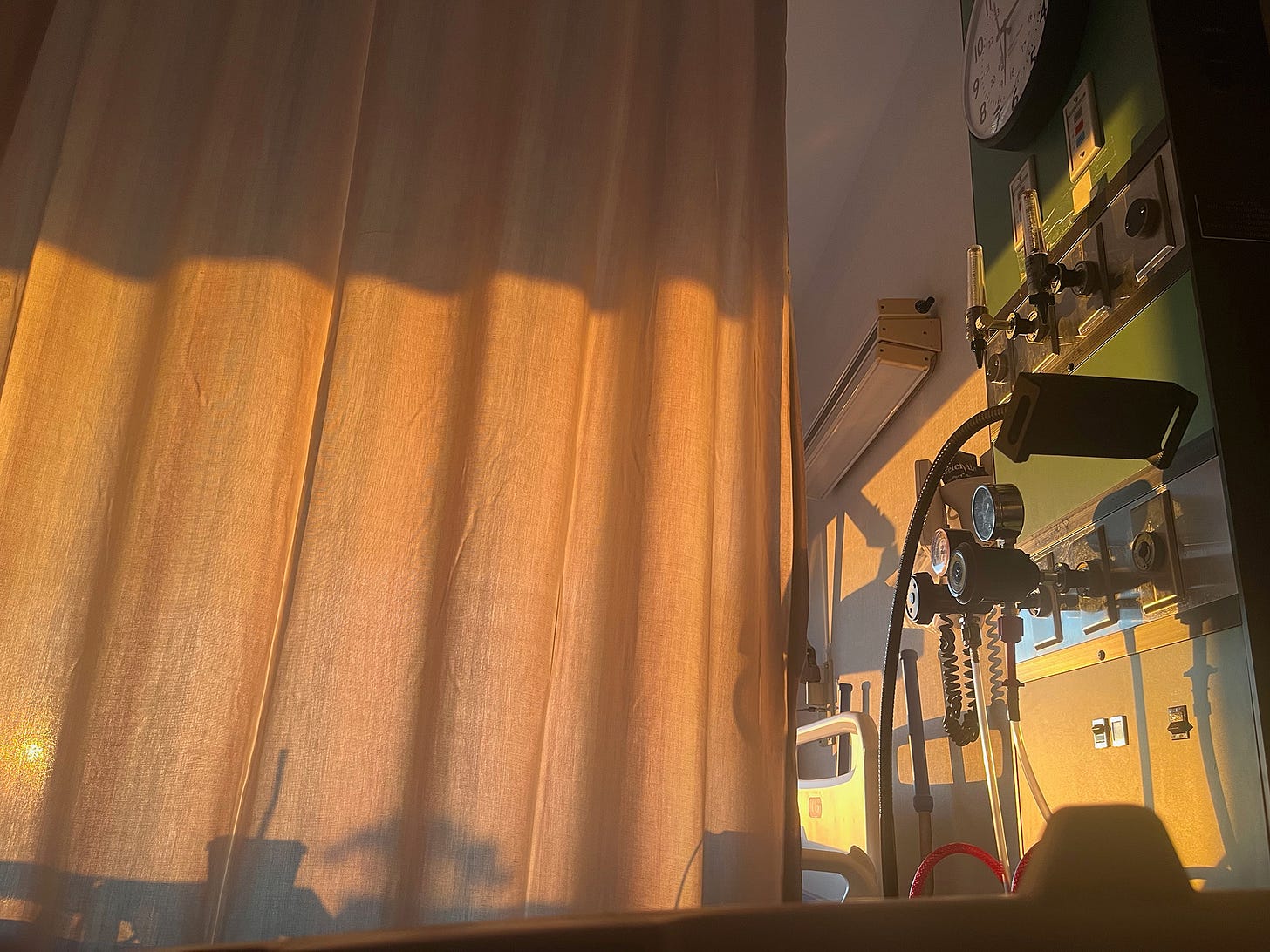 Early dawn light illuminates the curtain in my hospital room. On the wall towards the head of the bed there's a myriad of medical tubes and dials hanging unused.