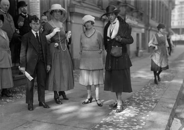 Men and women in 1920s clothes, standing in a Berlin street.