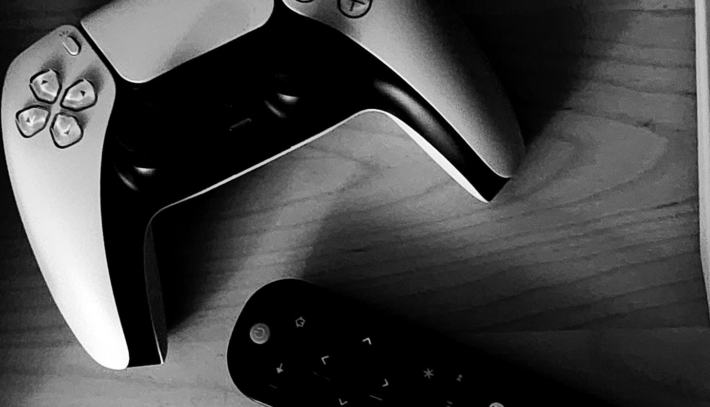 Black and white image of a video game controller and a "smart" TV remote control.