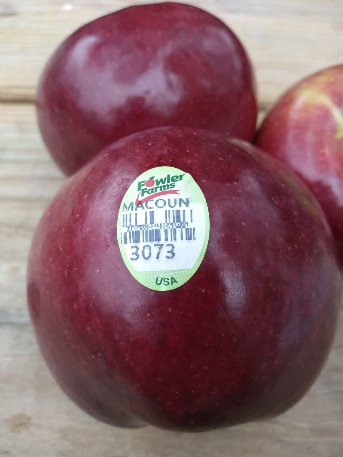 3 Macoun apples on a wood picnic table.