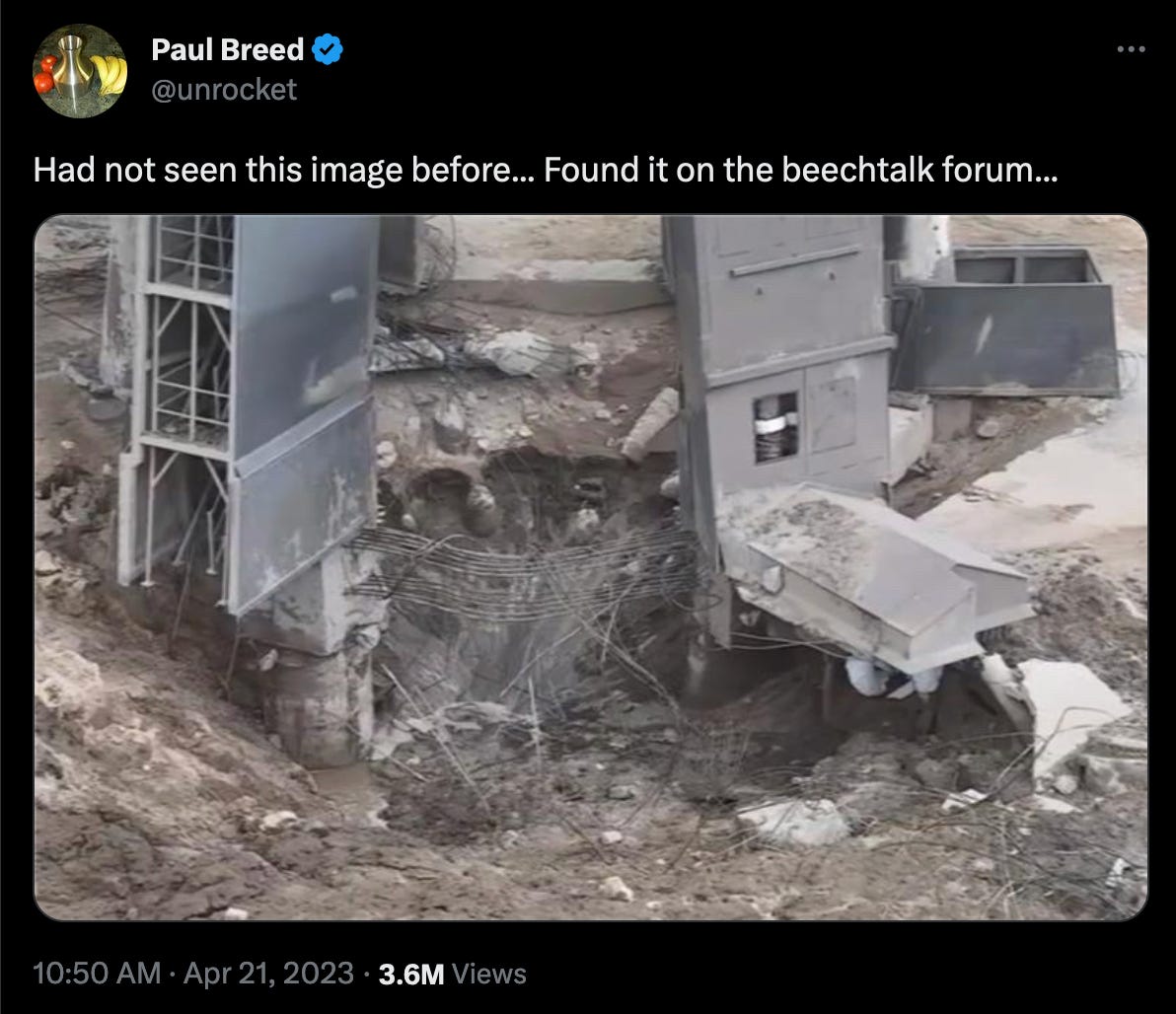 A screenshot of a Tweet by Paul Breed (@unrocket). The text of the tweet reads "Had not seen this image before... Found it on the beechtalk forum." The photo shows a large crater, with rebar still strung across it.
