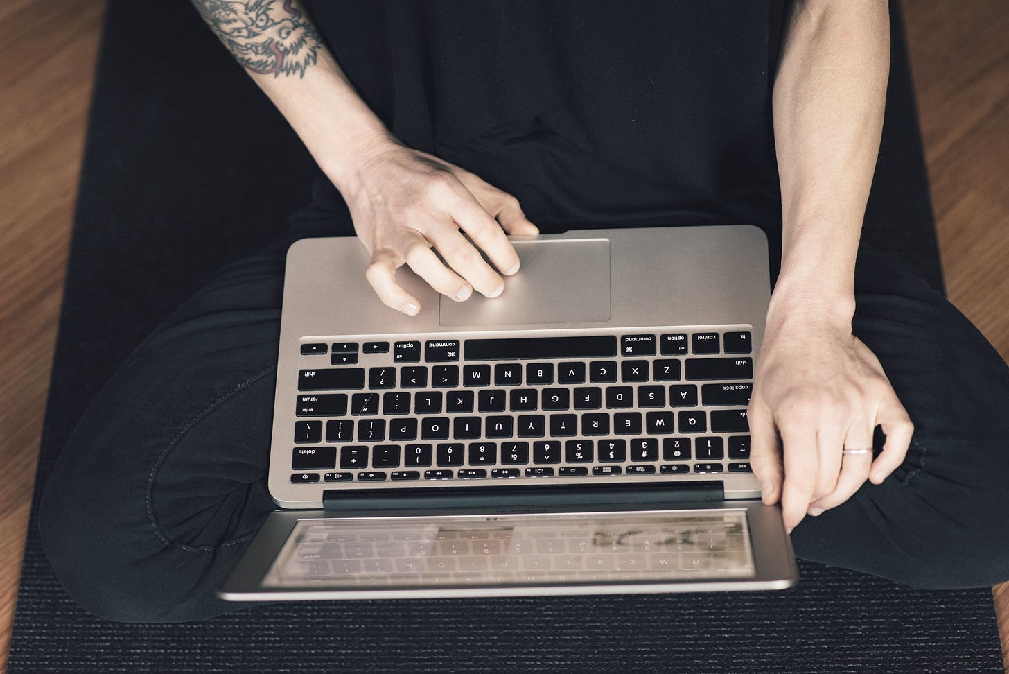 author sitting cross-legged typing on laptop