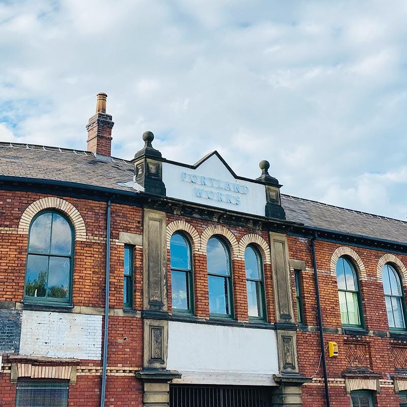 The outside of Portland Works in Sheffield with the sign in light blue in the centre of the photo
