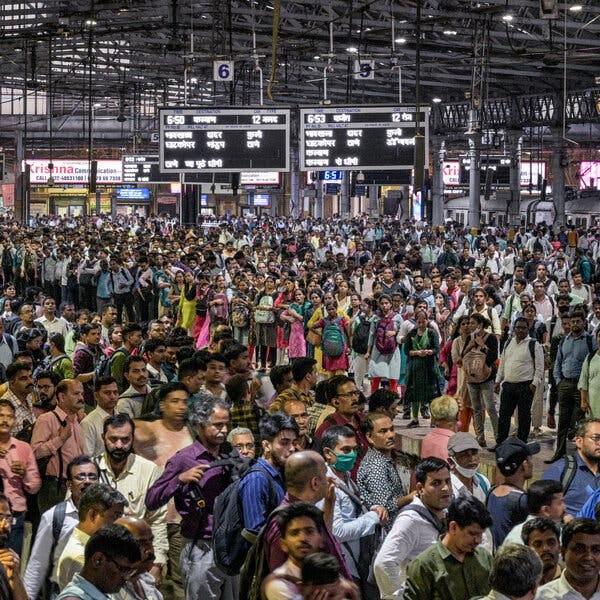A crowd of people standing at a platform waiting for a train in Mumbai, India. 