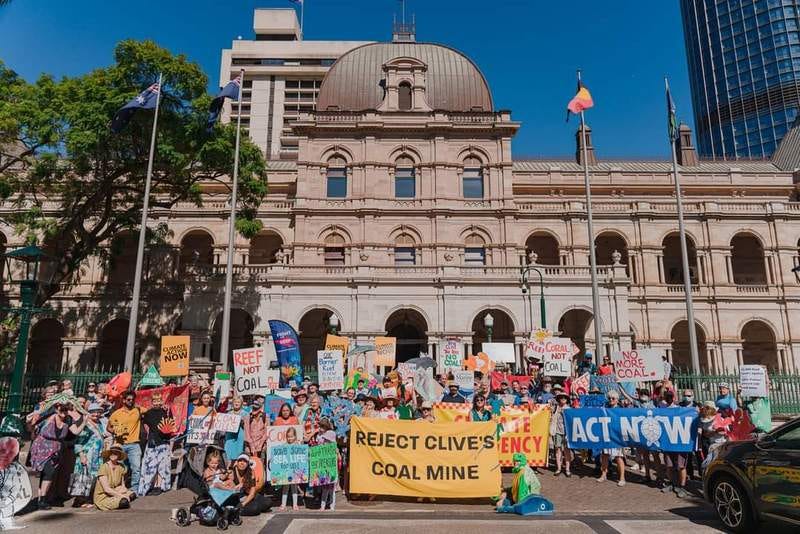 Photo of a group of people gathered outside of Qld Parliament House April 2021, with lots of colourful signs