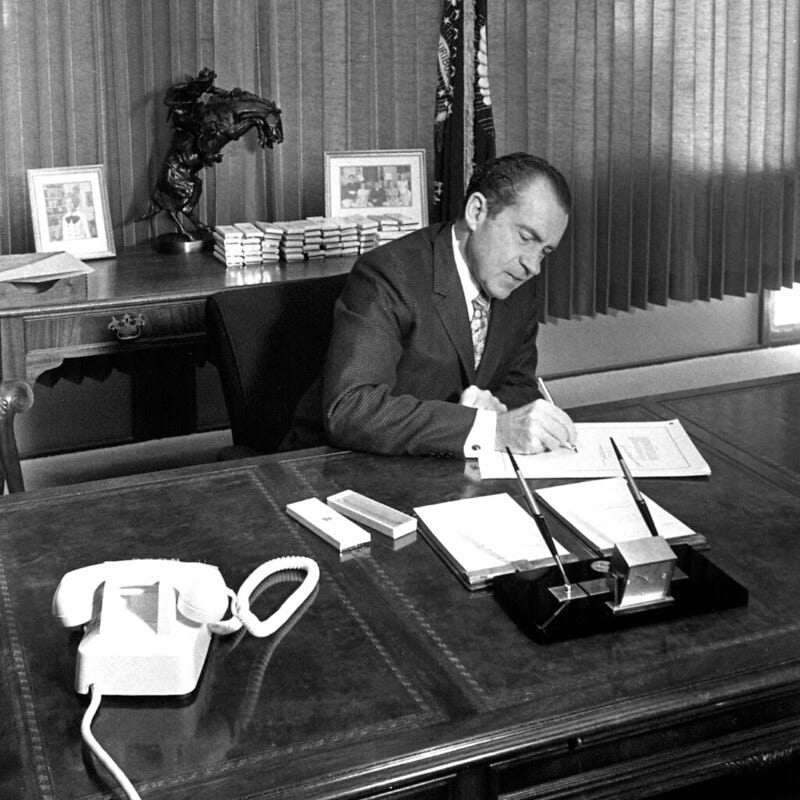 president nixon sitting at a desk signing a law