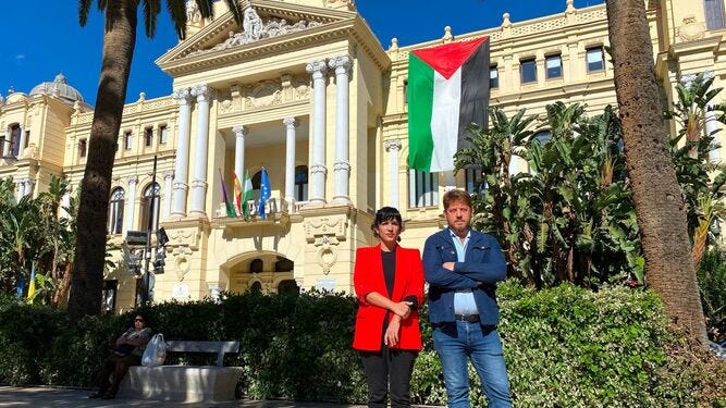 Toni Morillas y Nicolas Sguiglia, de Con Málaga, posando con la bandera frente al Ayuntamiento.