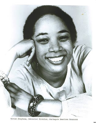 Photo of Vivian Stephens, smiling in a black and white photo. She is a radiant Black woman with short-cropped hair, posing casually with her head resting on her hand.