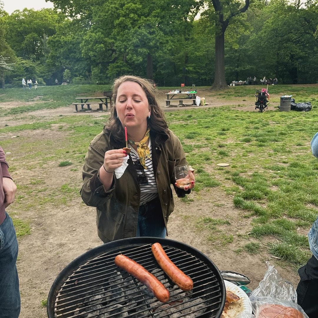 Brianna by a BBQ of sausages.