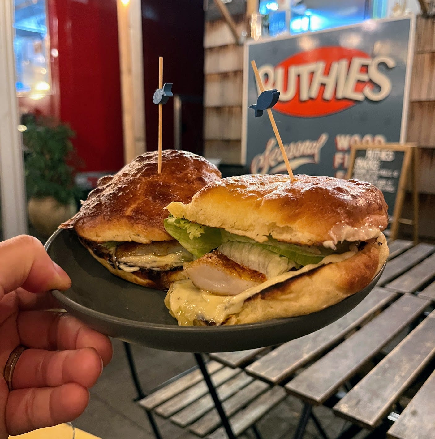 Hand holding plate of two fish sliders