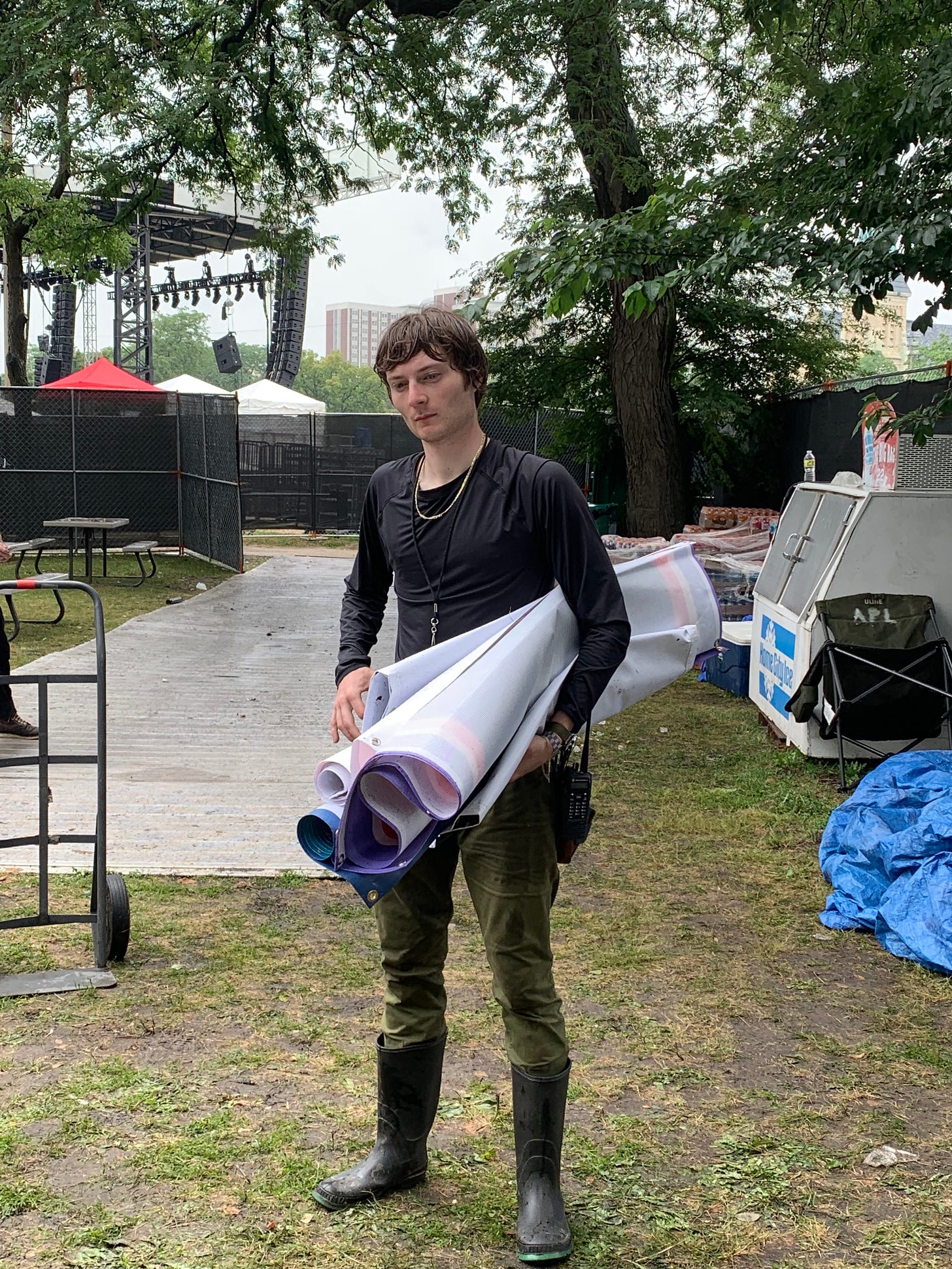 A photo of me, wet from rain, holding sponsor banners at Pitchfork Music Festival.