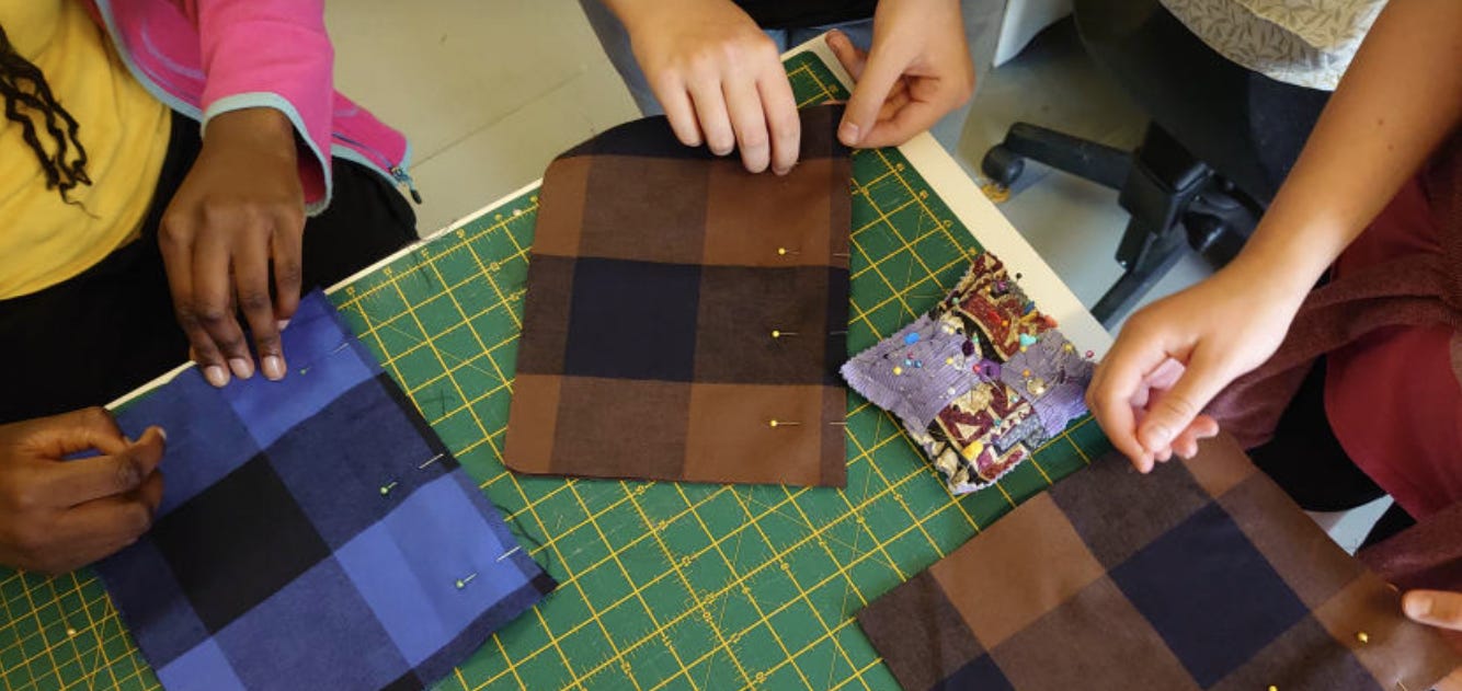 children's hands working on pinning fabric pieces together on a green cutting mat