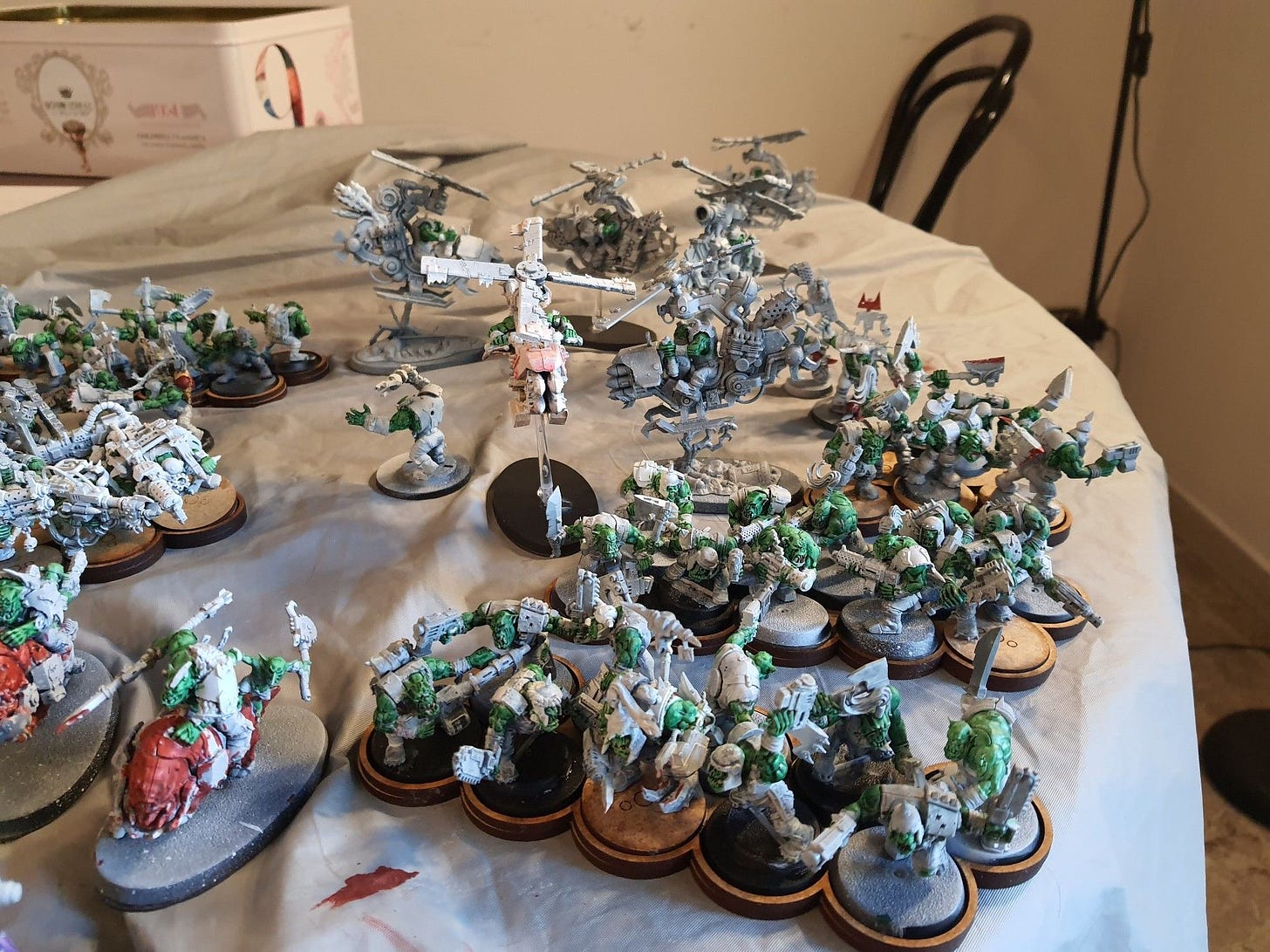 Some Orks, all primed in white and with their green skin painted with contrast paint. The picture shows three 10-Boyz squads, a kitbashed Weirdboy, six Deffkoptas, a kitbashed Warboss, some Lootas, and five Nobz with their ammo runt.