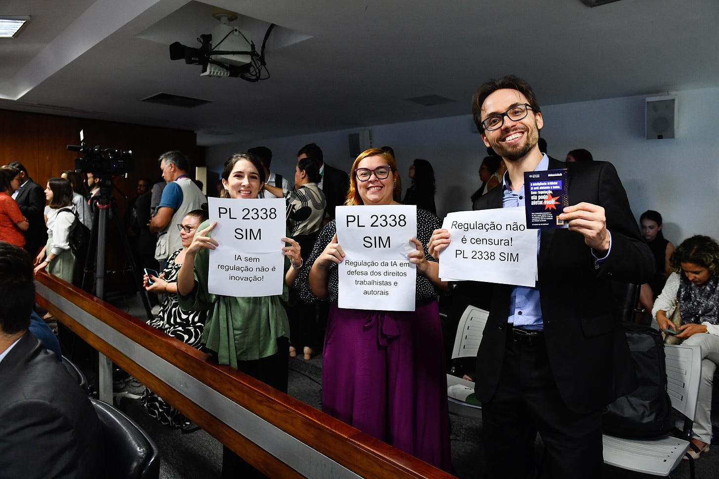 Da esquerda para direita, Clarissa Mendes, Raquel Saraiva, integrantes do IP.Rec (Instituto de Pesquisa em Direito e Tecnologia do Recife) seguram cartazes em defesa do PL 2338/23 em comissão do Senado.