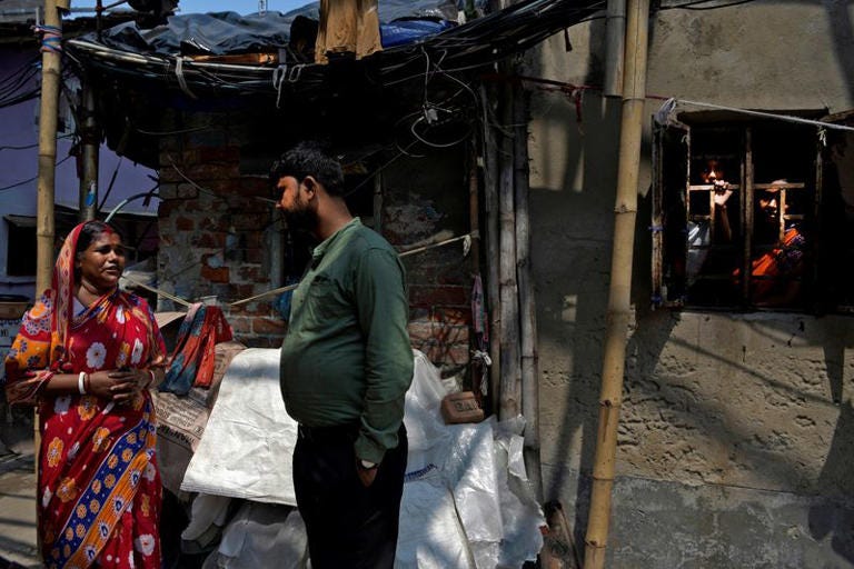 Partha Chaudhury, a worker of India's ruling BJP, intereacts with a resident of a slum during the party's outreach program in Kolkata