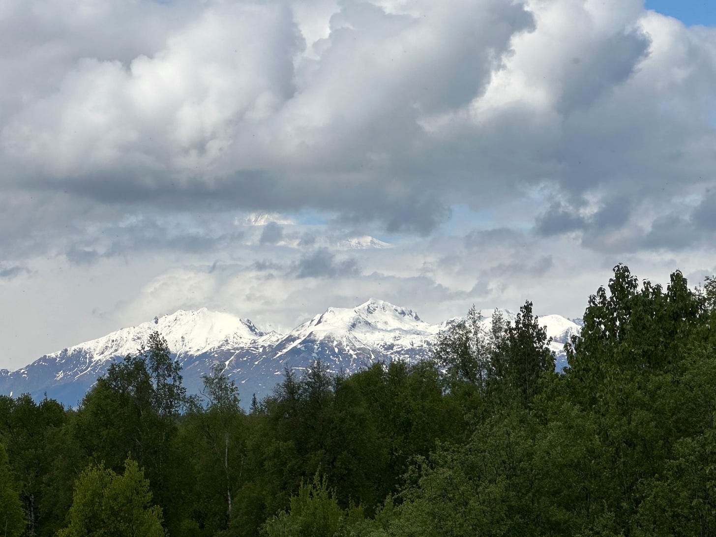 Mountain range with peak of Denali showing through the clouds.