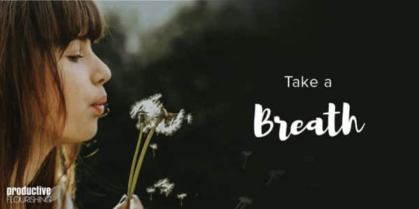 A woman blows a dandelion puff from the left-hand side of the frame. Text Overlay: Take A Breath
