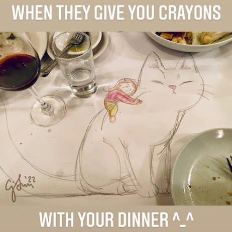 Crayon Cat Sketch Image 2 is a photo of a crayon drawing of a girl with a barrette hugging a giant cat, drawn on a dinner table topped with paper, background containing a wine glass and plates. Caption reads, "When they give you crayons with your dinner." sketch by Connie Sun, cartoonconnie, 2022.