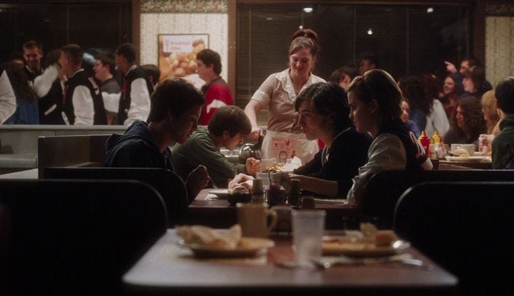 This may contain: a group of people sitting at tables in a restaurant with food and drinks on the table