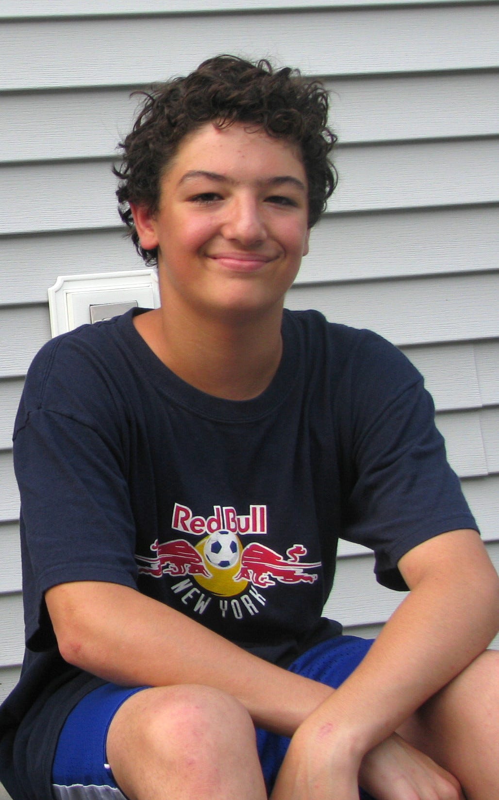 Young man sitting on a step with blue t-shirt and shorts