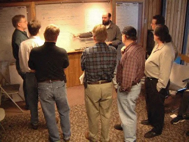 A bunch of guys standing at a whiteboard.