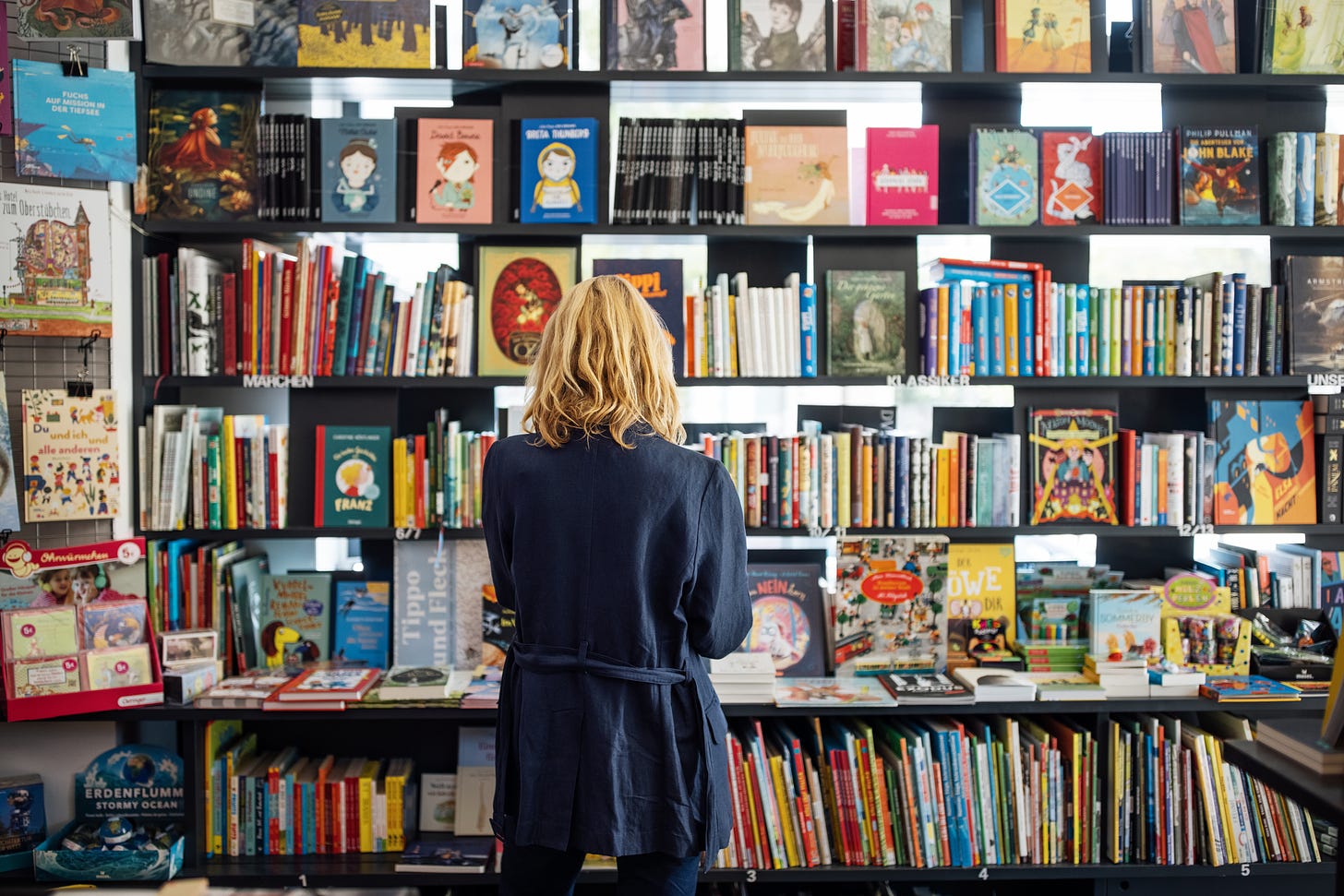 A woman browses the selection of books at a bookstore.