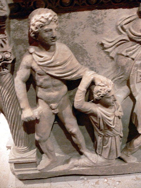Color photograph of a relief sculpture. A semi-nude figure is dragging another by his hair.