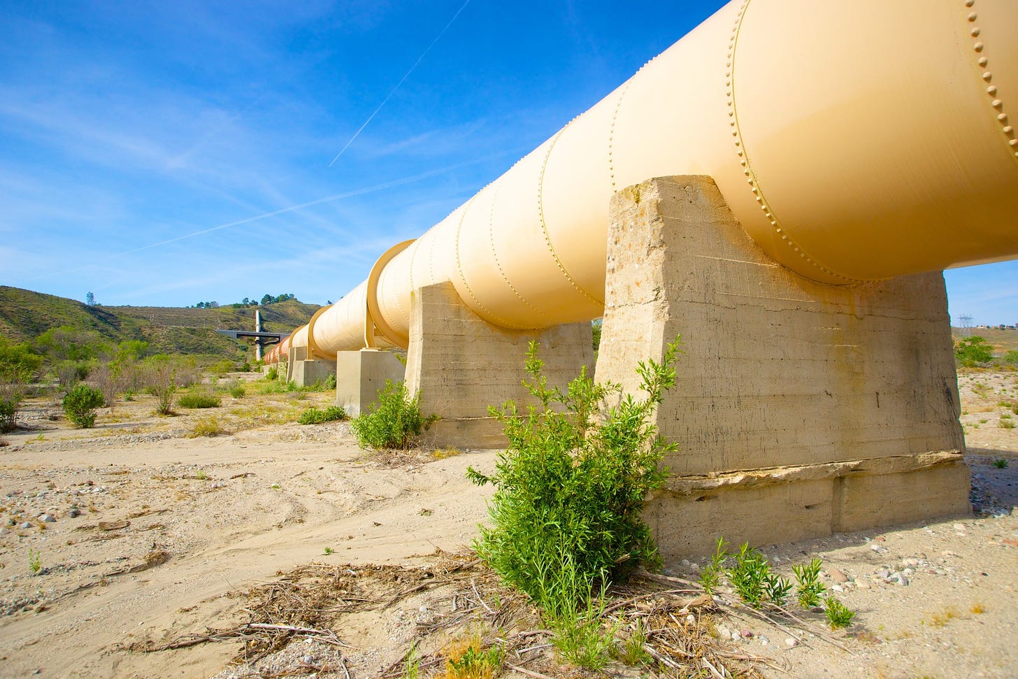 A yellow pipeline against a blue sky in the desert. Photo by Ken Kistler.