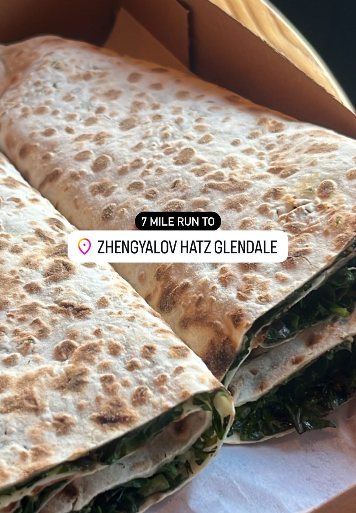 Instagram story that reads "7 Miles to Zhengyalov Hatz" with an image of herb-filled pita wraps in the background.