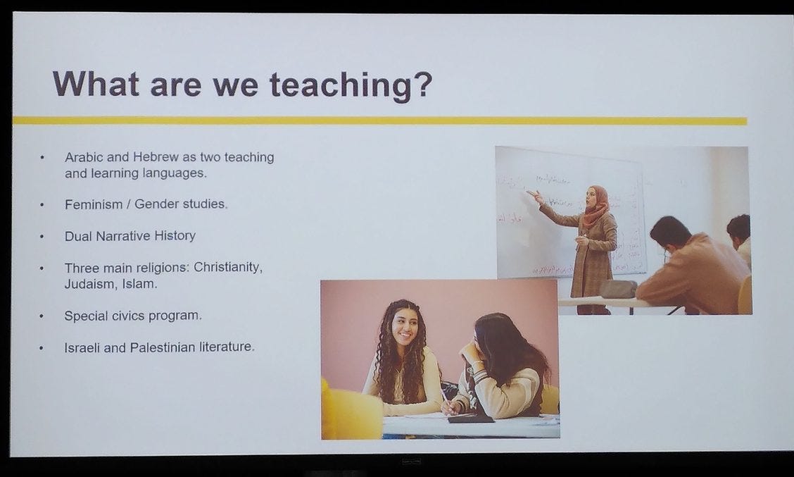 Photo of a projected power point slide with heading: What are we teaching? bullet points: Arabic and Hebrew and two teaching and learning languages, feminism/gender studies, dual narrative history, three main religions: Christianity, Judaism, Islam; Special civics program, Israeli and Palestinian literature. Includes 2 photos, one of hijabi teaching students, pointing at white board. Two young women both with long dark hair in conversation at a shared table.