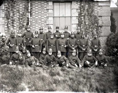 a black and white photo of police officers posing in front of a building