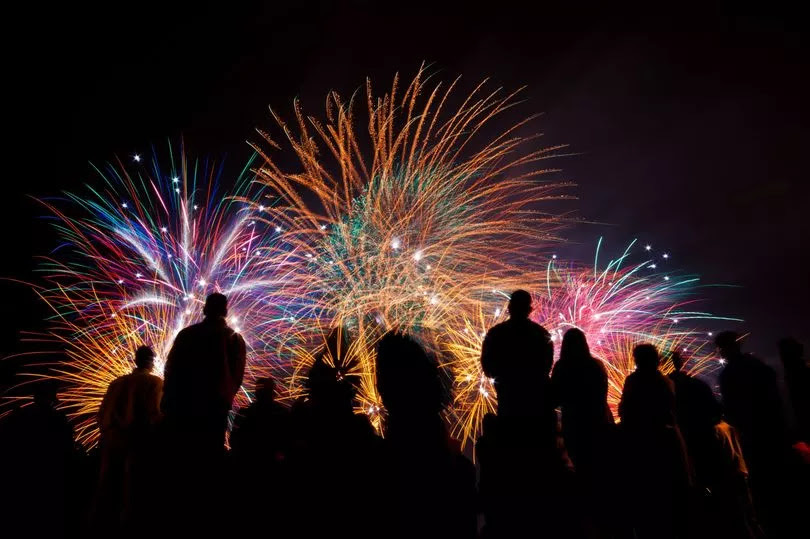 Fireworks against a black sky with people silhouetted in black