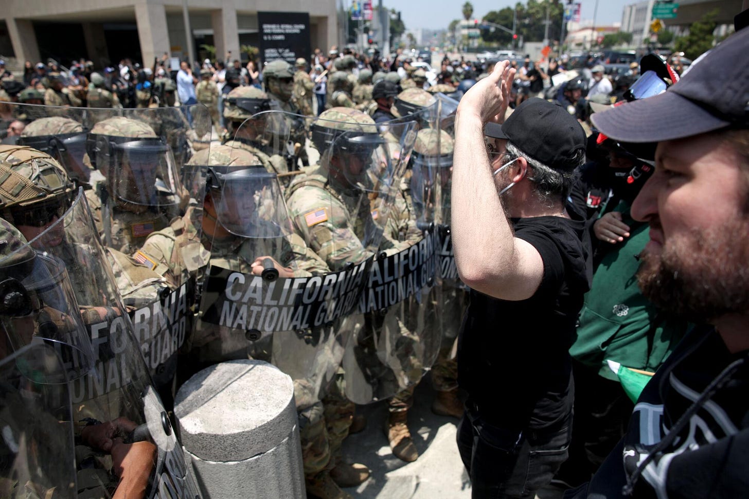 Protesters shout at a line of California National Guard troops in riot gear. Protesters shout at a line of California National Guard troops in riot gear.