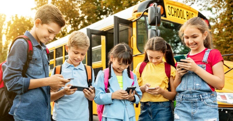 school bus with kids using cellphones