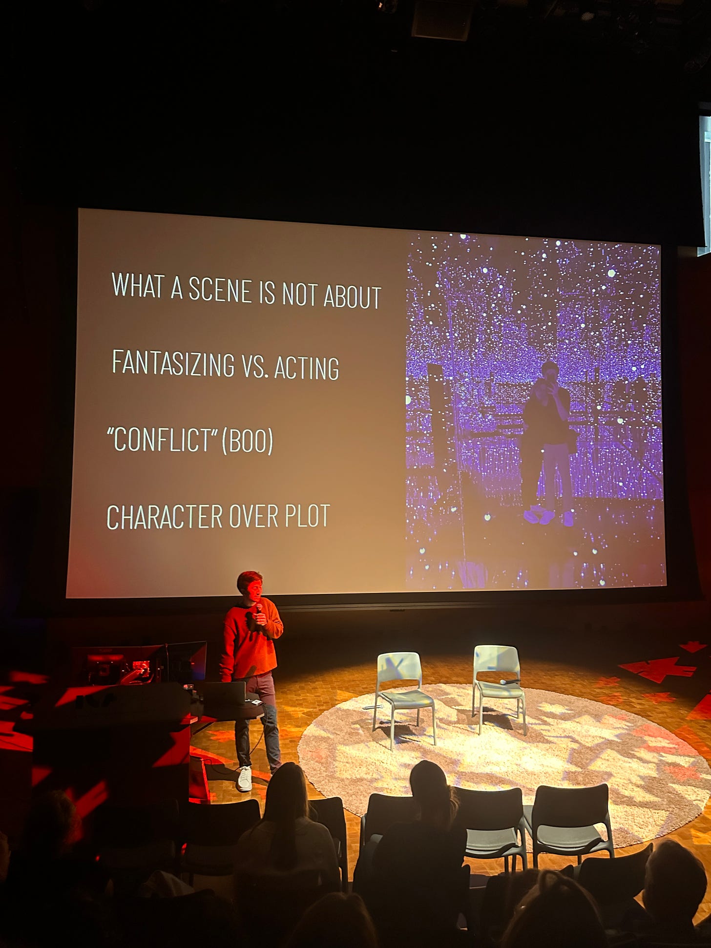 Image shows a man on stage in front of a circular carpet. A screen behind him, Davy Gardner, talks about different part of writing 