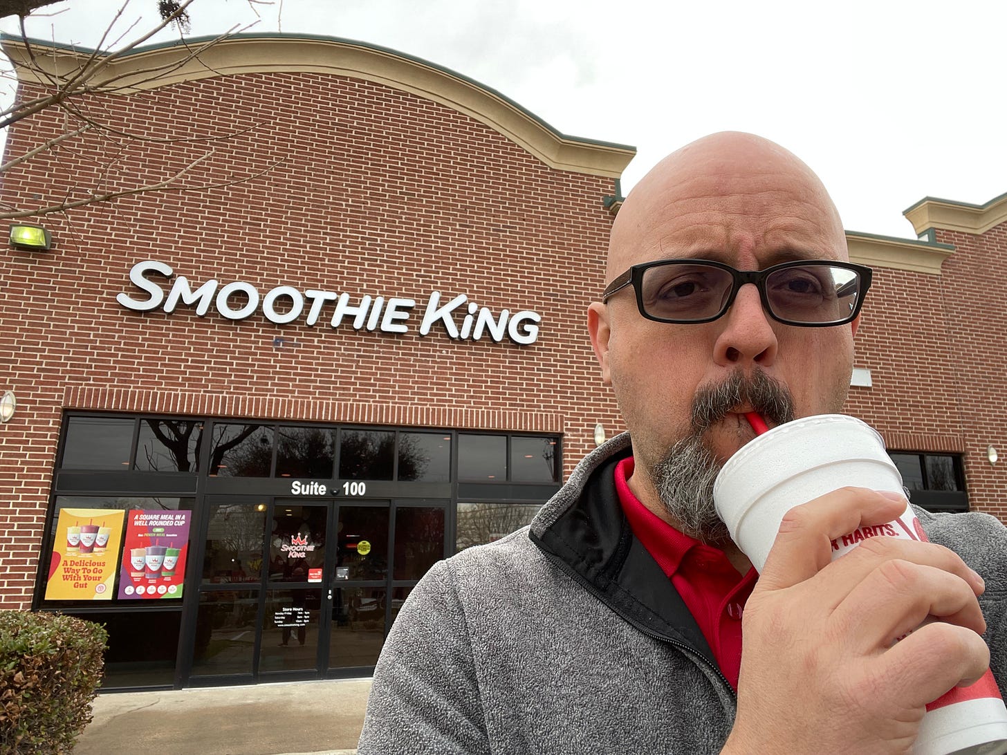 A bald bespectacled doofus enjoying a Smoothie