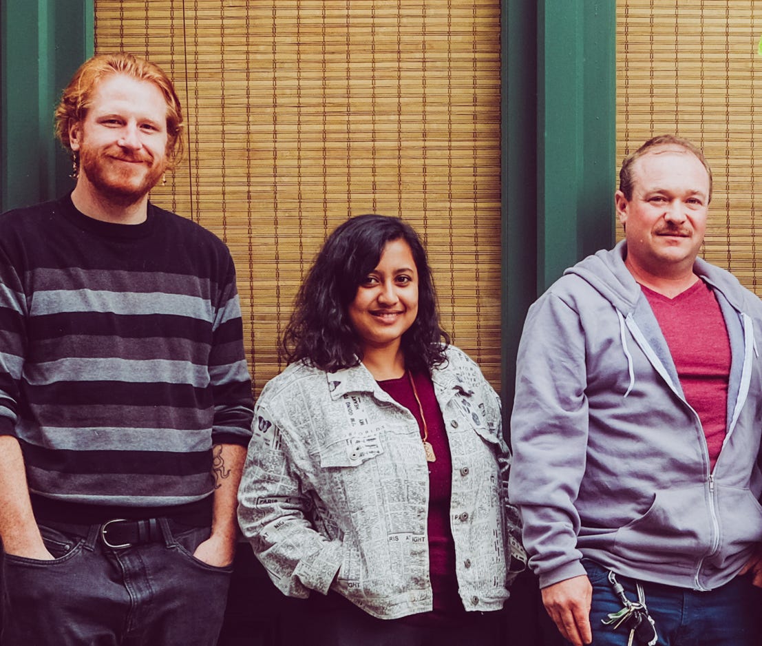 Dustin Godfrey, Brishti Basu, and David P. Ball stand in a row against a window with closed blinds