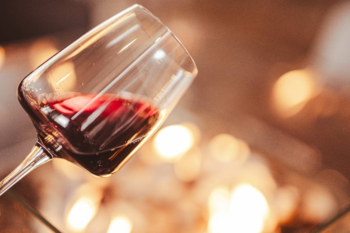 Close-up of a red wine glass with firelight in the background, radiating warmth and comfort.