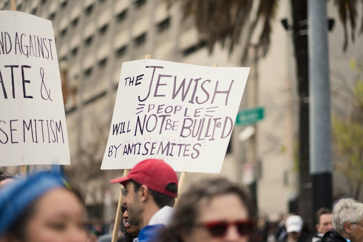 Man in protest carries sign denouncing antisemitism