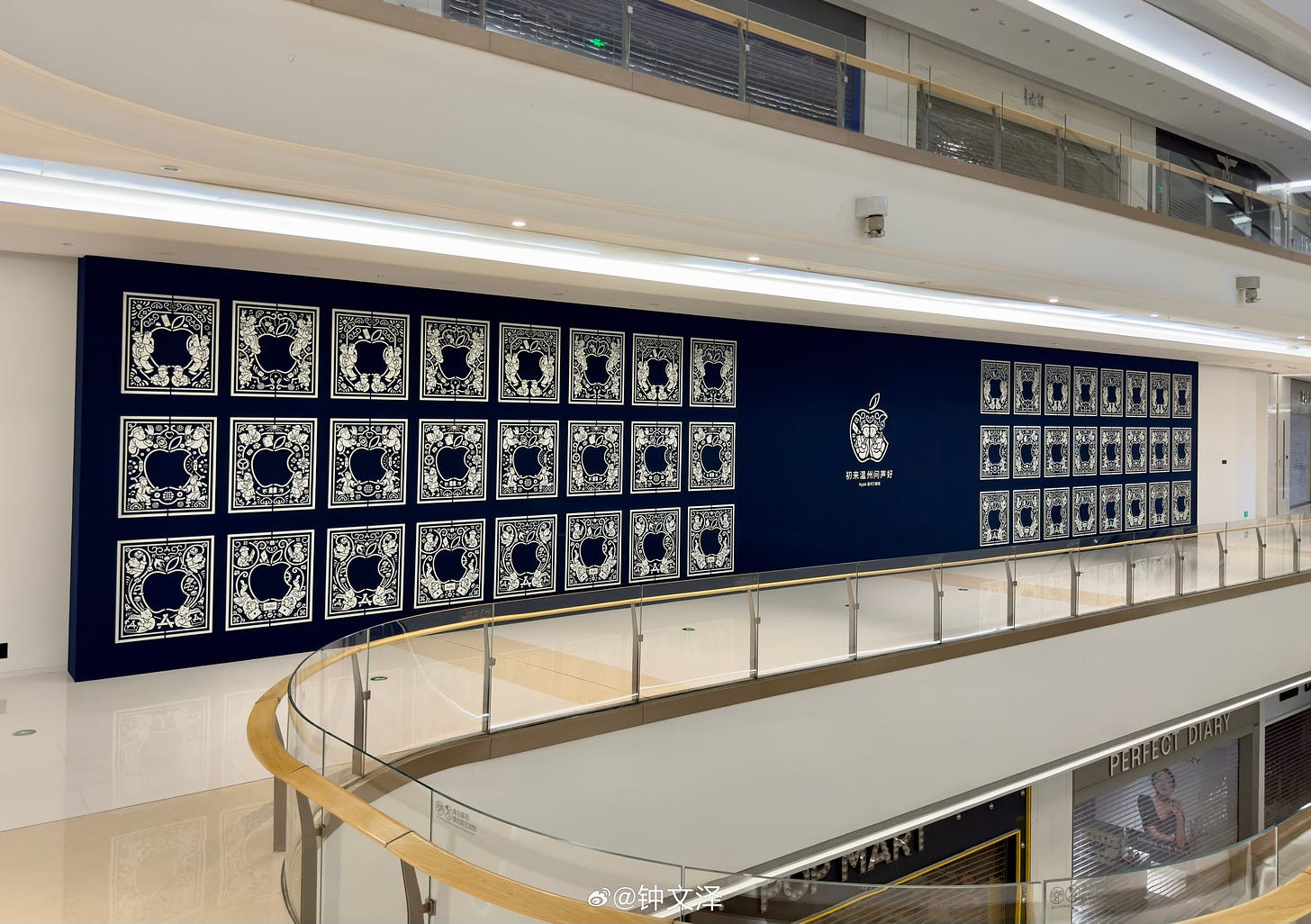 The exterior of Apple MixC Wenzhou is covered in banners celebrating the store opening. The artwork has a blue background and references a traditional textile technique from Wenzhou.